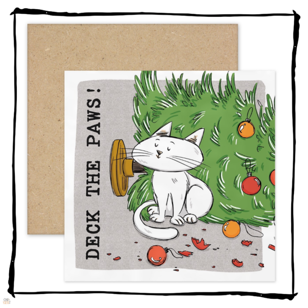 White cat sitting beside a fallen Christmas tree and broken baubles on a Deck the Paws Christmas card.